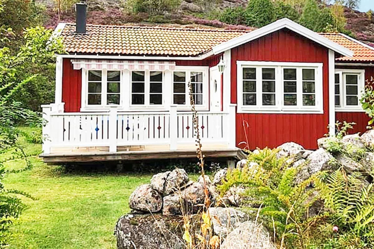 A red wooden house with a white porch and multiple windows.