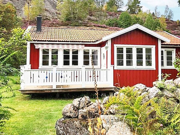A red wooden house with a white porch and multiple windows.