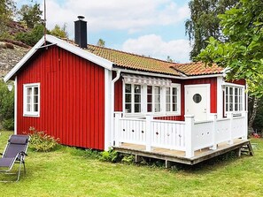 A red wooden house with a white porch and a chimney.
