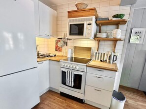Une cuisine compacte équipée d’un four à micro-ondes, d’une cuisinière, d’un four et d’un évier.