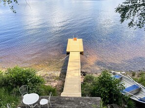 A wooden dock extending into a calm body of water, with a small boat docked on the right. - 4 Person Holiday Home in Bullaren (Bullaren)