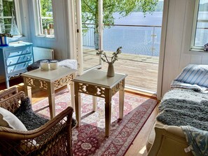 A room with a view of a lake, a blue dresser, a wicker chair, and a bed with a blue and white striped blanket. - 4 Person Holiday Home in Bullaren (Bullaren)