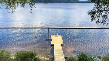 A wooden dock extending into a calm lake with a clear view of the surrounding landscape.