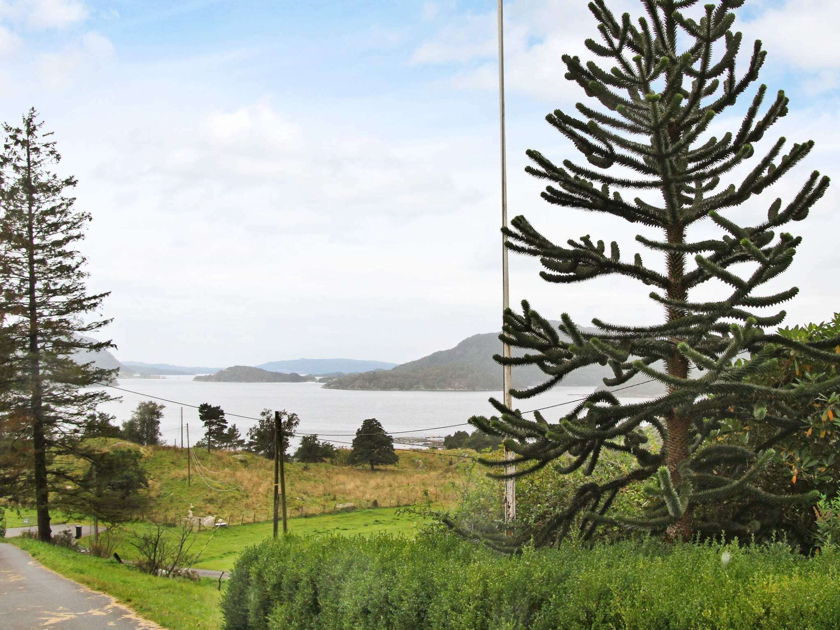 A road with a view of a lake and mountains in the distance.