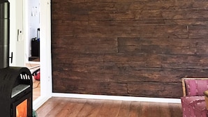 Een kamer met een houten vloer, een open haard en een roze gestoffeerde stoel.