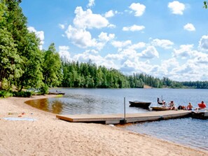 Un lago con un muelle de madera y una playa de arena.