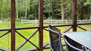 A wooden deck with a table and chairs, surrounded by a white fence and trees. - Holiday Home in Gränna (Gränna)