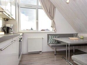 A modern kitchenette with a window, a radiator, a bench, and a table.