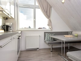 Et moderne tekøkken med et vindue, en radiator, en bænk og et bord.