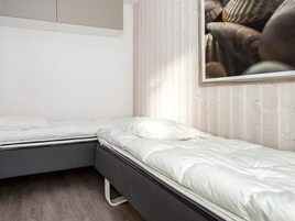 Un dormitorio con dos camas individuales, un panel de pared de madera y un cuadro enmarcado.