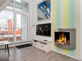 Una sala de estar moderna con chimenea, televisor y un ventanal grande.