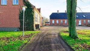A rural road leading to a row of brick houses with a lamp post and trees on either side.