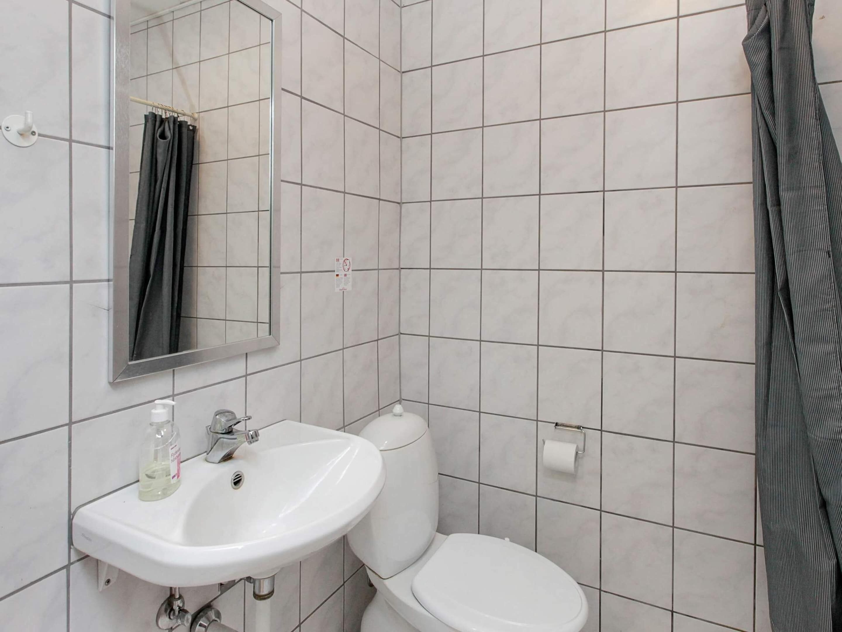 A bathroom with a white sink, mirror, and toilet.