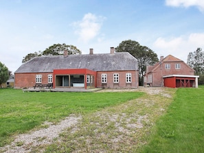 A red-brick building with a large open porch and a separate red-roofed garage.