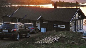 Et toetagers hus med et skråt tag, en garage og en indkørsel med to parkerede biler.