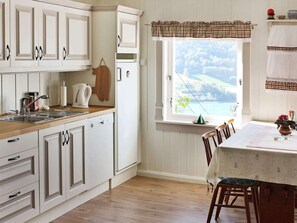 A kitchen with white cabinets, a wooden countertop, a window with a view, and a dining area with a table and chairs.