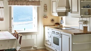 A kitchen with a window, wooden cabinets, a stove, and a dining table with chairs. - 6 Person Holiday Home in Otta (Sel)