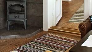 A room with a wooden floor, a patterned rug, a small stove, and white cabinetry. - 6 Person Holiday Home in Otta (Sel)