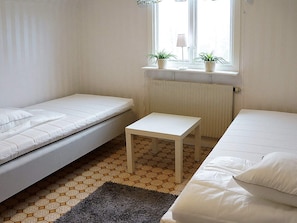 A small, clean room with two beds, a small table, and a window with plants. - Holiday Home in Berga (Berga)