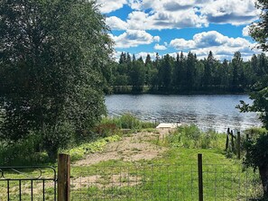 A lake surrounded by trees, a grassy area, and a fenced path. - Holiday Home in Berga (Berga)