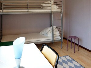Une chambre avec un lit superposé, une table et une chaise.