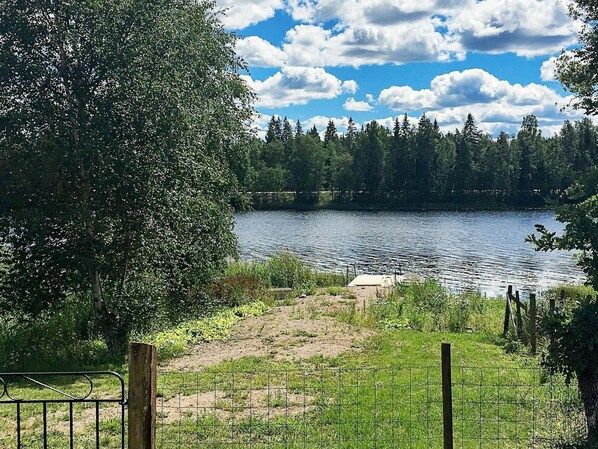 Ein See, umgeben von Bäumen und einer Wiese mit einem Zaun.