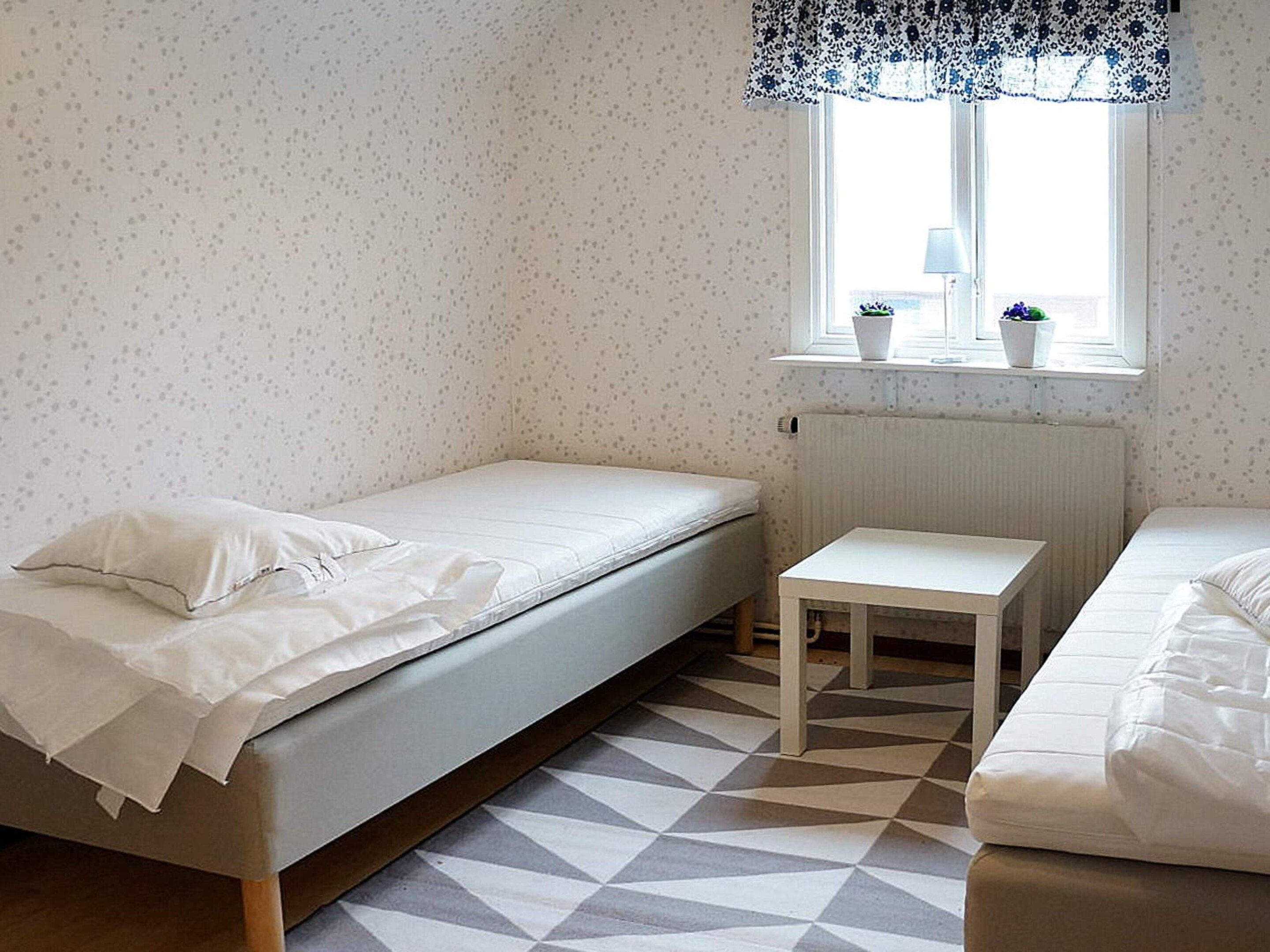 A room with a single bed, a small table, and a window with a view.