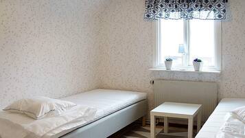A room with a single bed, a small table, and a window with a view.