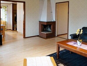 A living room with a fireplace, a sofa, a coffee table, and a dining area with chairs. - Holiday Home in Berga (Berga)
