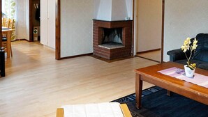 Un salon avec une cheminée, un plancher en bois, un canapé et une table basse.