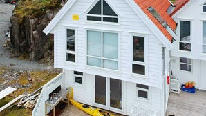 Un edificio blanco con techo rojo, un pequeño muelle y un kayak amarillo.