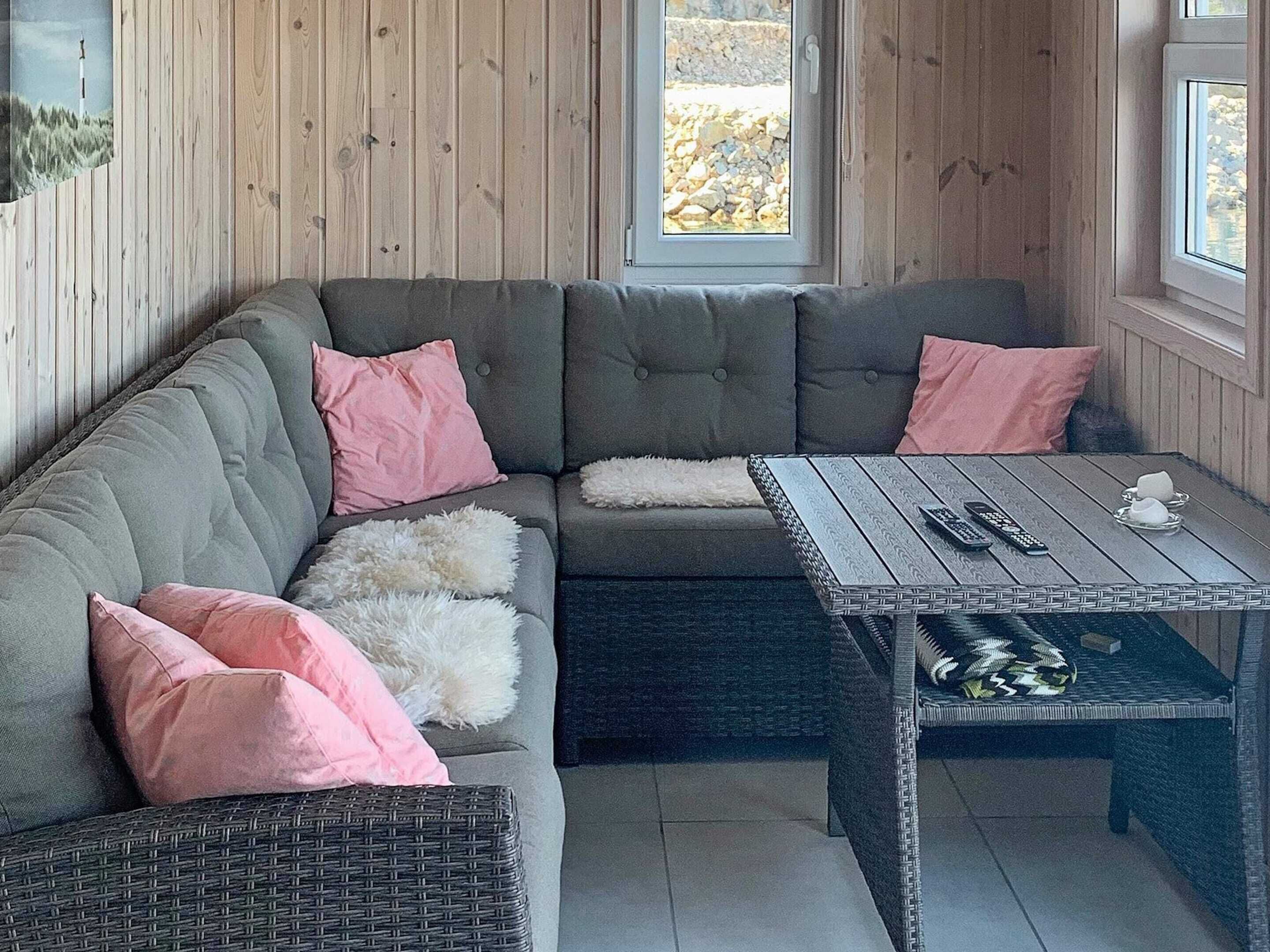 Une pièce chaleureuse avec un canapé d’angle, une petite table et un fauteuil en osier.