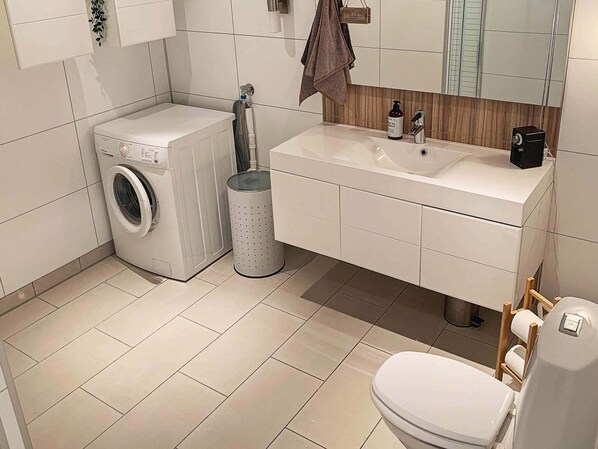 A modern bathroom with a washing machine, sink, and toilet. - 5 Star Holiday Home in Urangsvag (Bomlo)