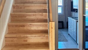 Una escalera de madera lleva a una cocina moderna con vistas al exterior.