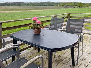 A deck with a table and chairs, overlooking a green field. - 5 Person Holiday Home in Varekil (Varekil)