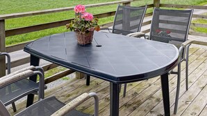 A deck with a table and chairs, overlooking a green field and hills. - 5 Person Holiday Home in Varekil (Varekil)
