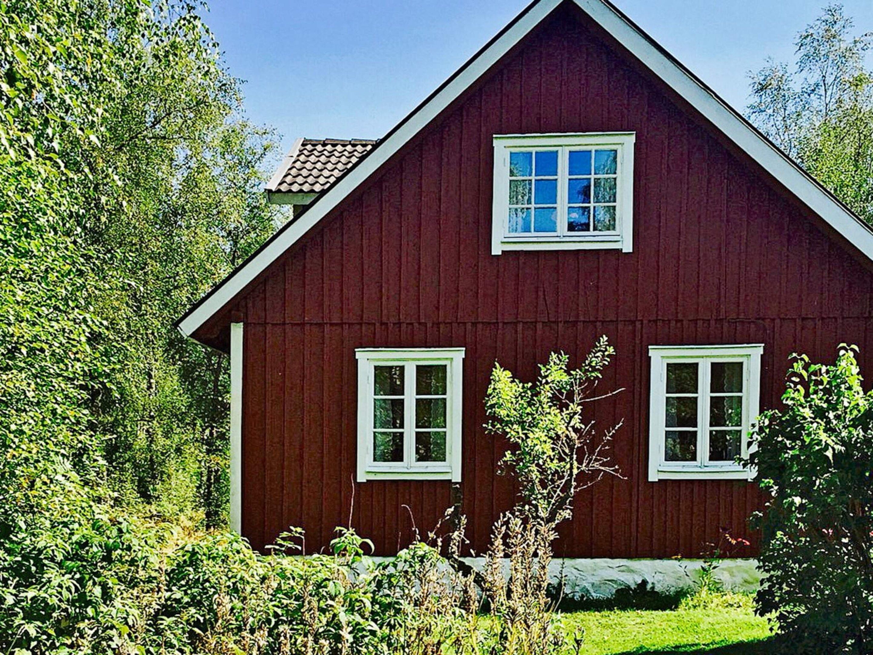 A red wooden house with a gabled roof and white trim.