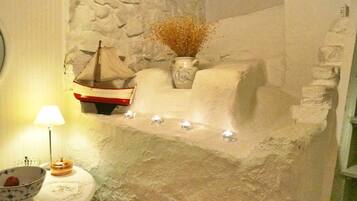 Pared de piedra con un estante que sostiene un jarrón y un modelo de barco.
