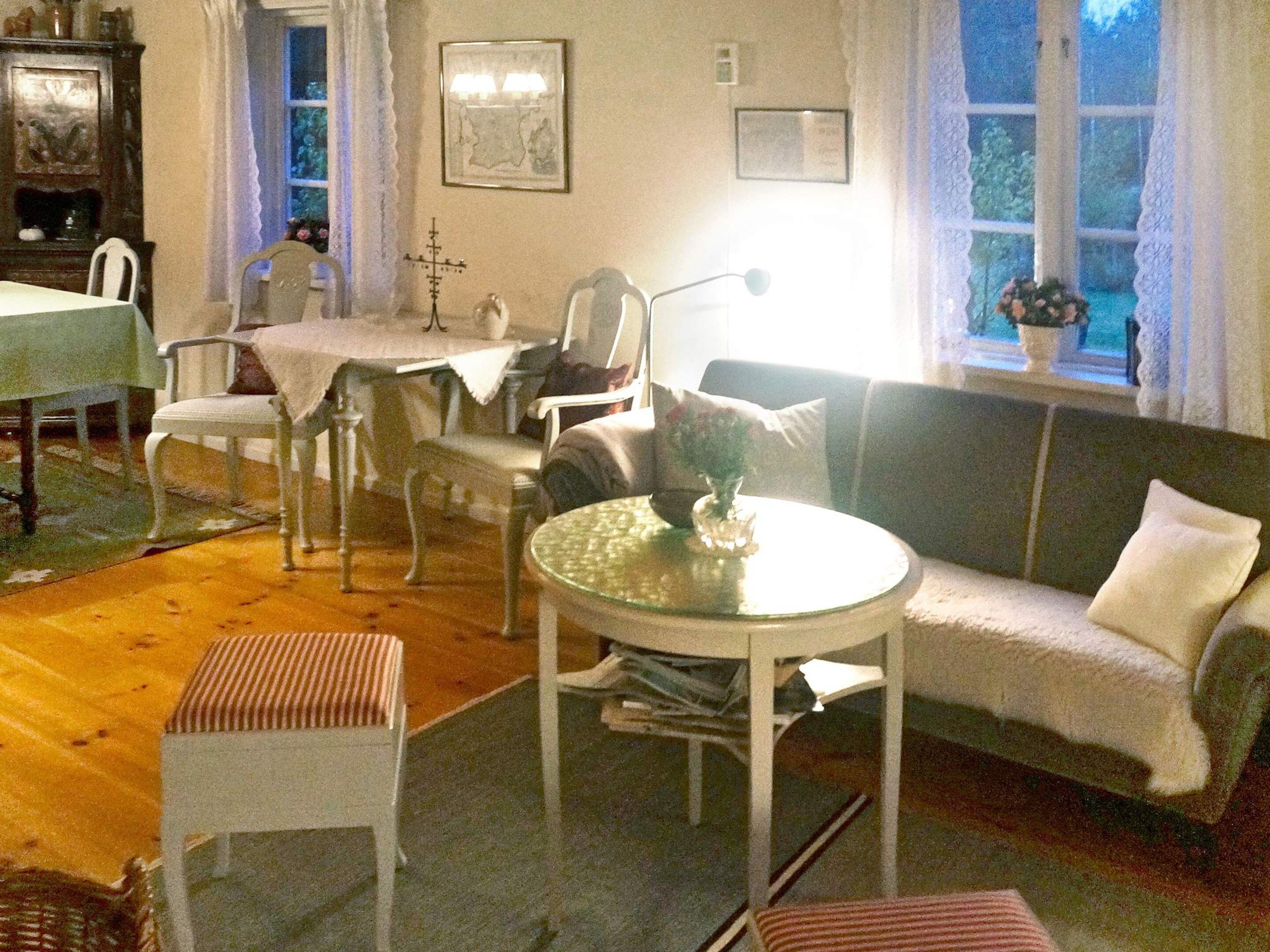 Un salon chaleureux avec une table ronde en verre, un canapé et un coin repas comprenant des chaises et une table.