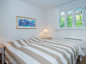 A bedroom with a bed, a nightstand, a lamp, a window, and a painting on the wall. - 4 Star Holiday Home in Aabenraa (Aabenraa)