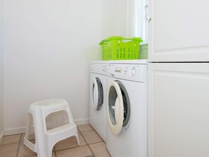 A laundry area with a washing machine and a small stool. - 4 Star Holiday Home in Aabenraa (Aabenraa)
