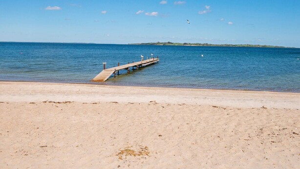 A beach with a wooden pier extending into calm blue waters. - 4 Star Holiday Home in Aabenraa (Aabenraa)