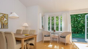 A dining area with a wooden table and chairs, a lamp, and a window with curtains. - 4 Star Holiday Home in Aabenraa (Aabenraa)