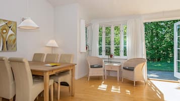 Uma sala de jantar com mesa e cadeiras de madeira, uma luminária e uma janela com cortinas.