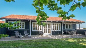 A house with a red-tiled roof, a covered patio with outdoor furniture, and a grassy yard. - 4 Star Holiday Home in Aabenraa (Aabenraa)