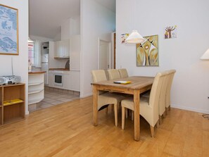 Una cocina moderna con armarios blancos y una mesa de comedor de madera con sillas.
