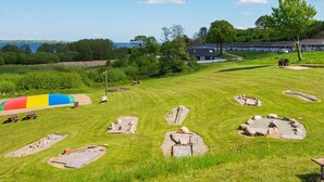 A grassy area with several stone structures, picnic tables, and a colorful slide. - 4 Star Holiday Home in Aabenraa (Aabenraa)