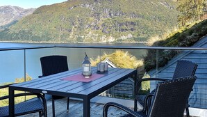 Une terrasse avec une table et des chaises, offrant une vue sur un lac et des montagnes.