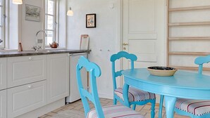 A kitchen with white cabinets, a sink, and a window. There is a blue table with chairs and a bowl on it. - Vintage Holiday Home in Svaneke near Small Harbor (Svaneke)