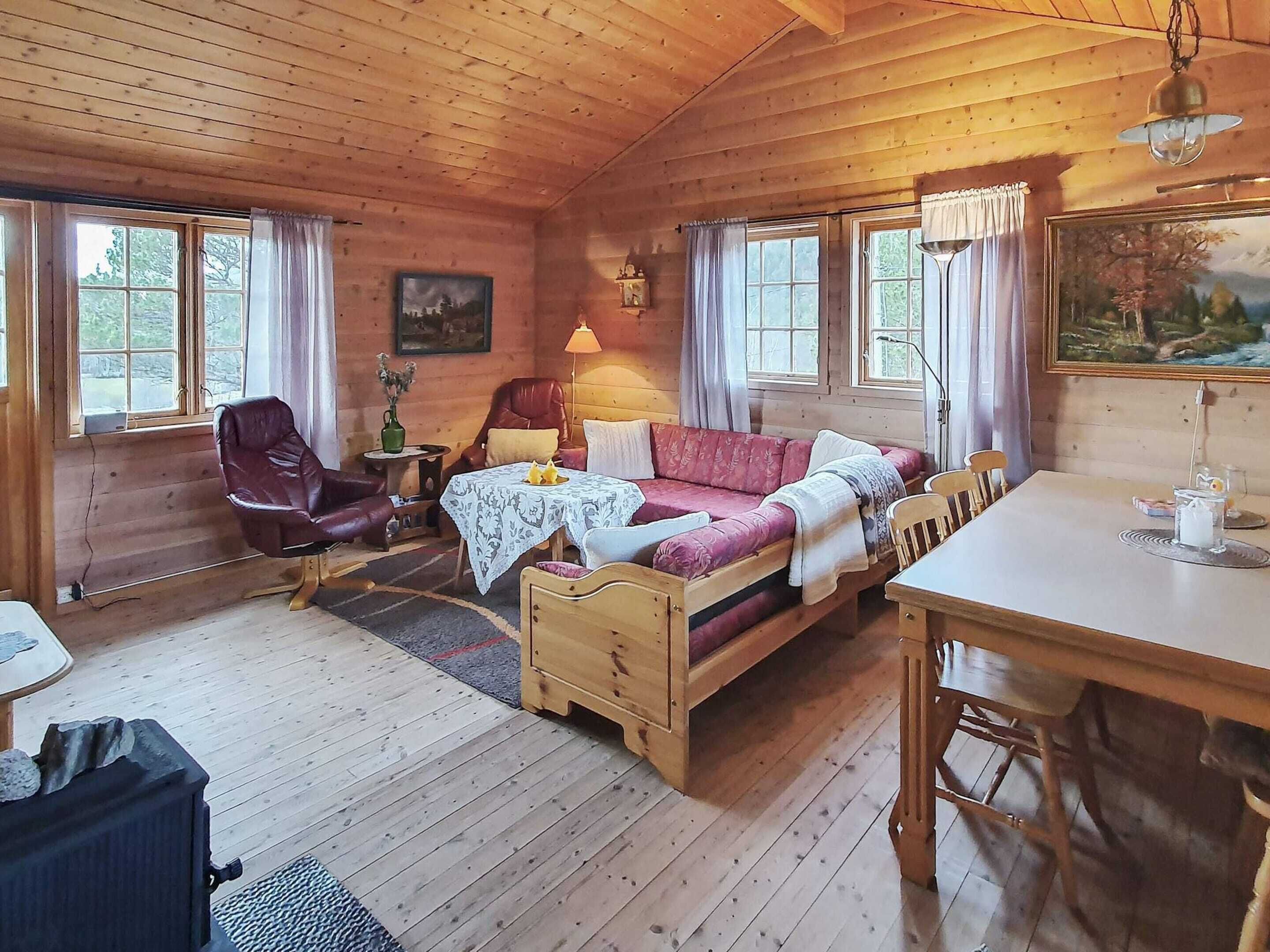 L’intérieur chaleureux d’un chalet avec un plancher en bois, un canapé, une table à manger et une cheminée.